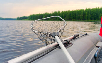 fishing on an inflatable boat. A paddle and a landing net on board. View from the Kayak to the beautiful lake